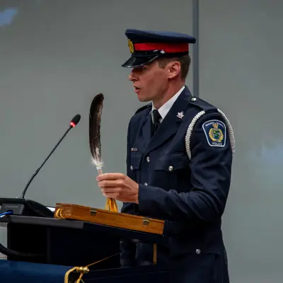 a police officer in formal uniform holding a feather while at a podium