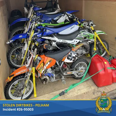 Two blue dirtbikes, two green dirtbikes, and an orange dirtbike in a trailer