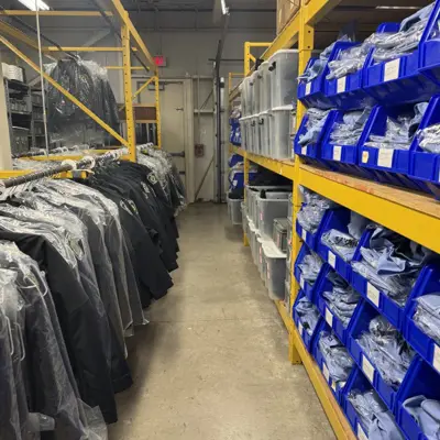 Rows of uniforms hanging on hangers and blue bins
