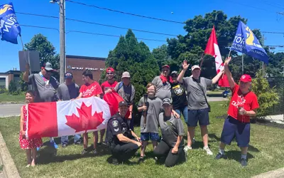 A group of people with Canada flags and blue flags and a matching grey shirts
