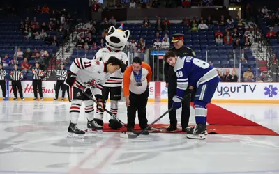Two players taking a ceremonial puck drop at a hockey game 