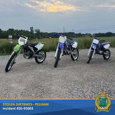One green and two blue dirtbikes on gravel