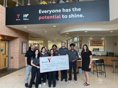 A group of students holding a large novelty cheque