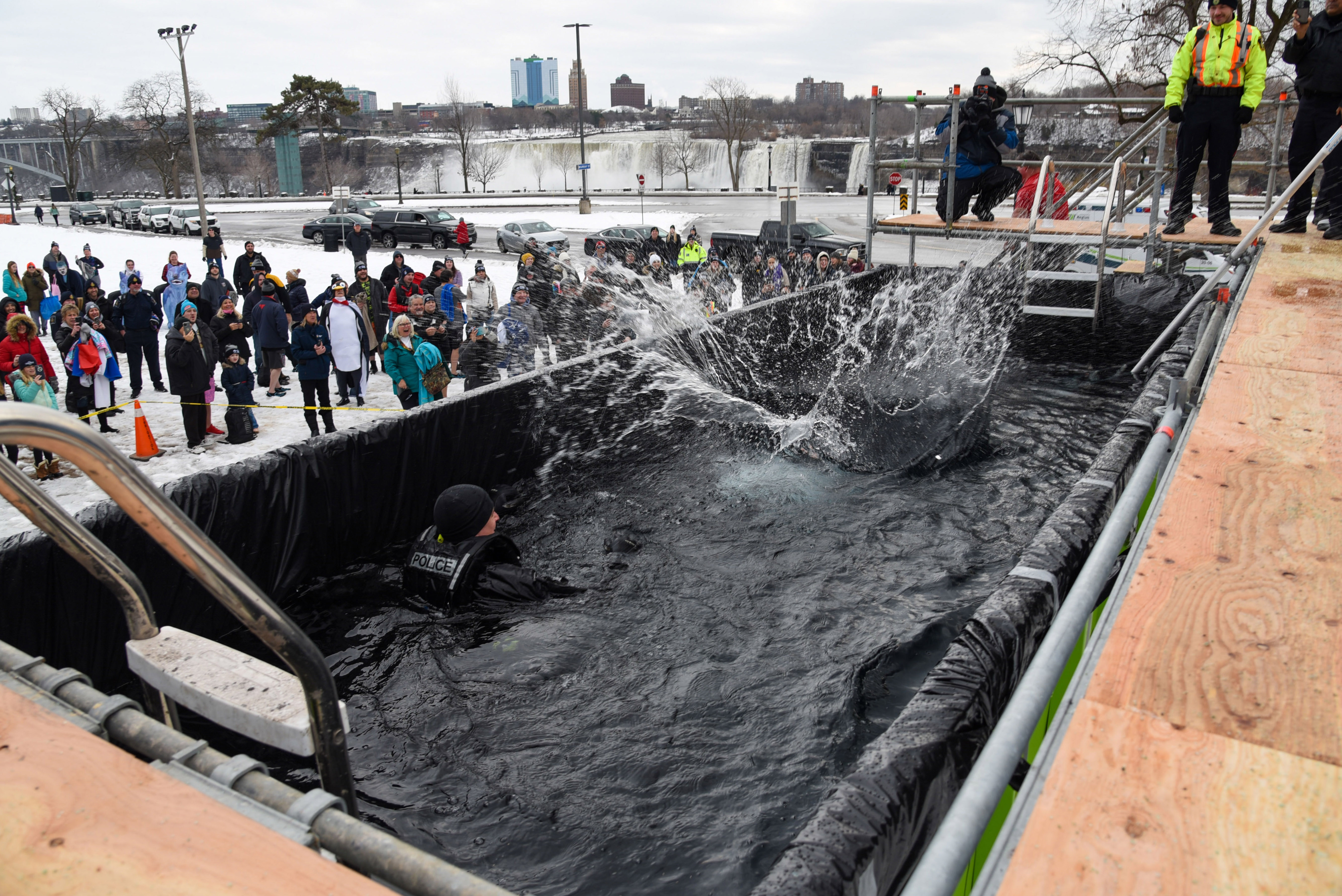A large splash in a pool of water with Niagara Falls in the background.